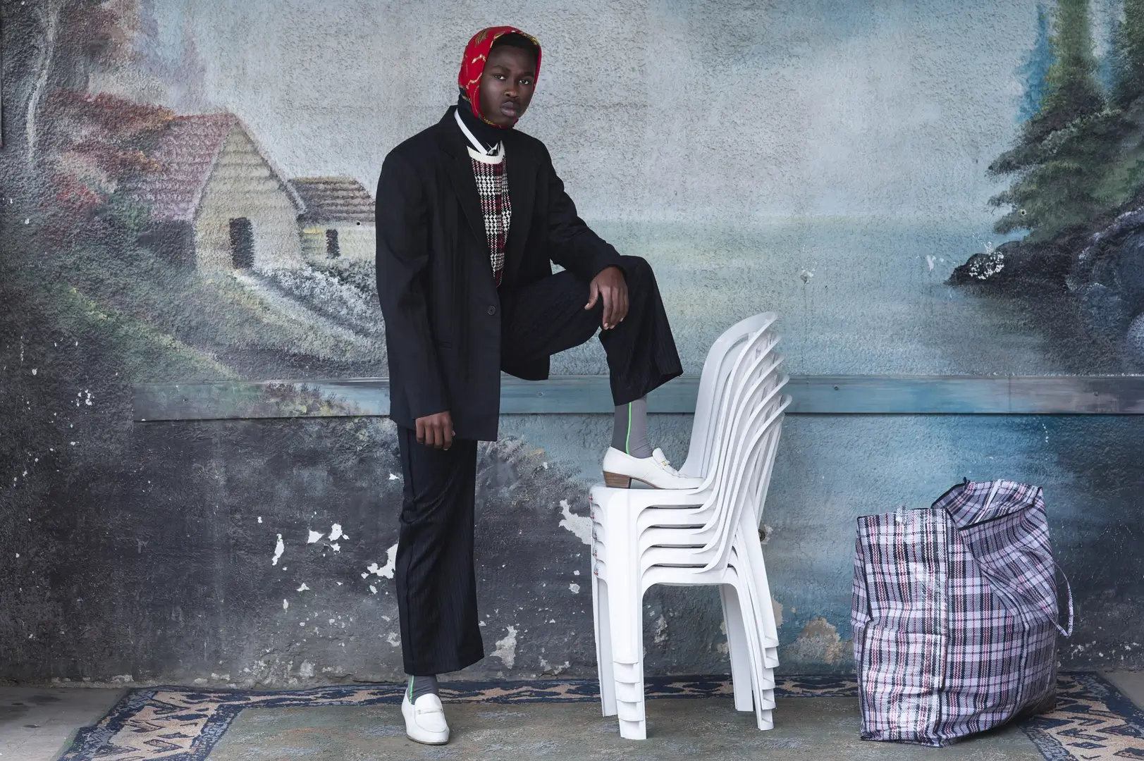 African man leaning on a pile of chairs