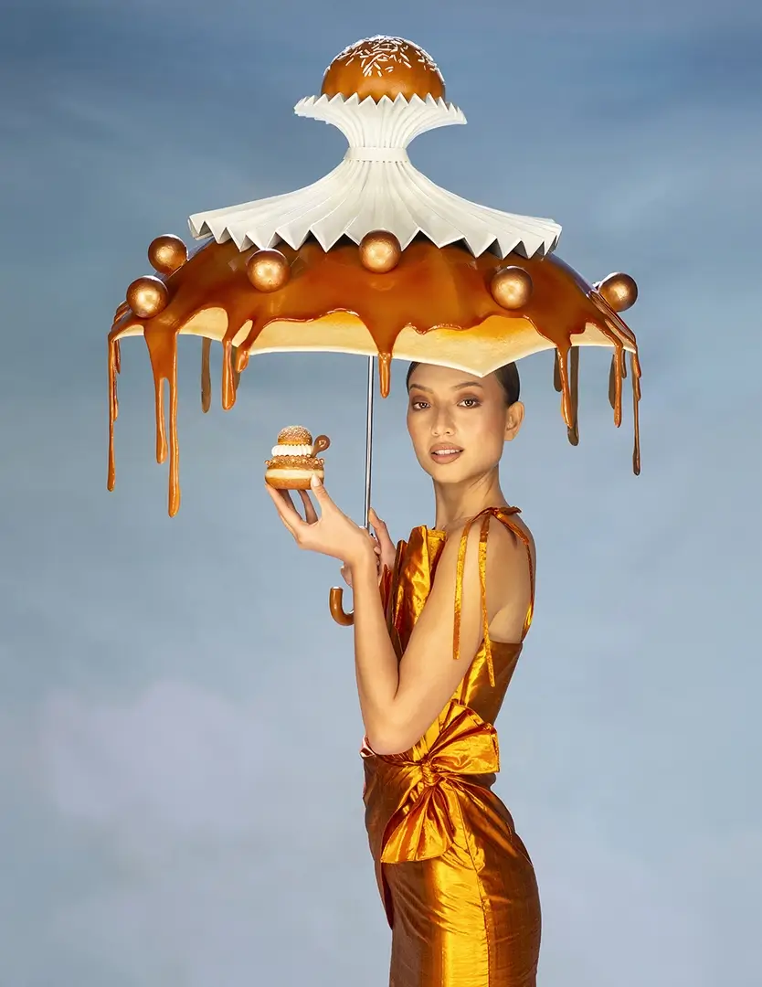 young woman holding a donut and an umbrella